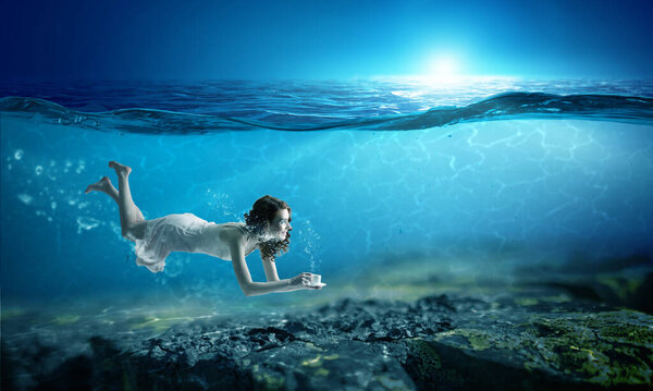 Woman holding a cup underwater