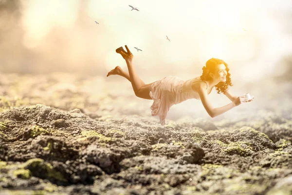 Young woman levitates while reading a book — Stock Photo, Image