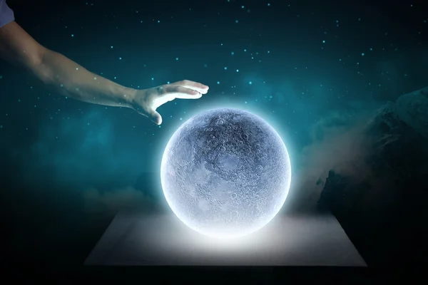 Mano humana tocando la luna azul brillante — Foto de Stock