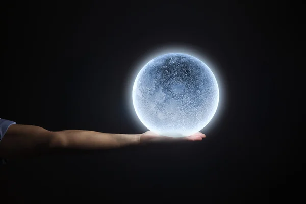 Человеческая рука держит голубую светящуюся луну — стоковое фото