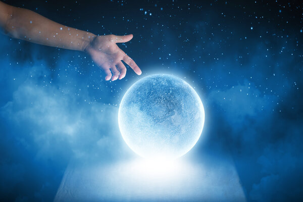 Human hand touching blue glowing moon