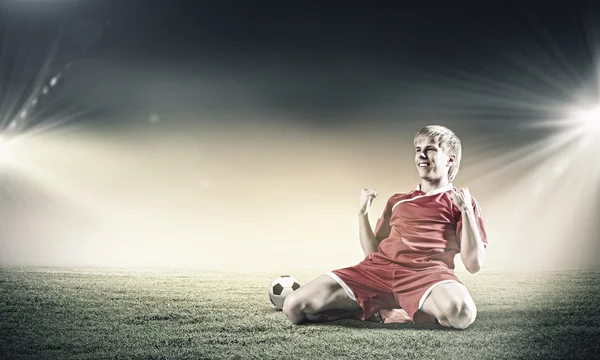 Fodboldspiller stående på knæ - Stock-foto