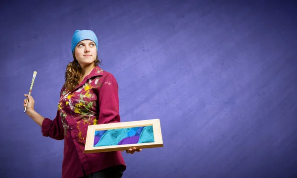 Painter holding frame with colorful splashes — Stock Photo, Image