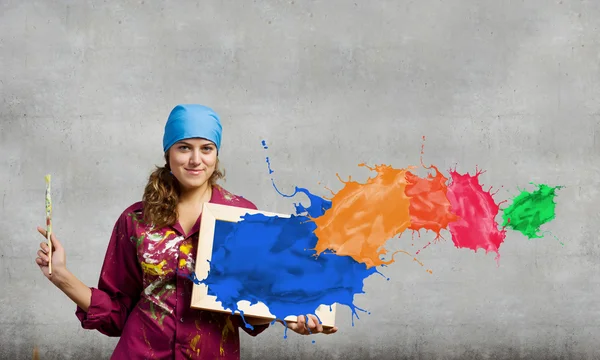 Painter holding frame with colorful splashes — Stock Photo, Image