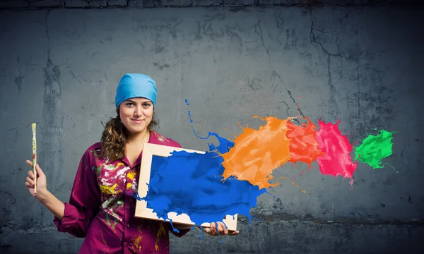 Painter holding frame with colorful splashes — Stock Photo, Image