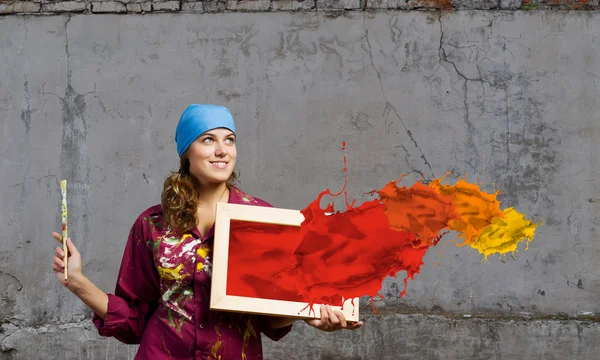 Painter holding frame with colorful splashes — Stock Photo, Image