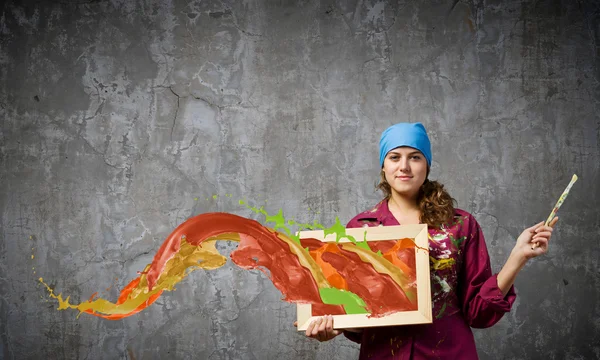 Painter holding frame with colorful splashes — Stock Photo, Image