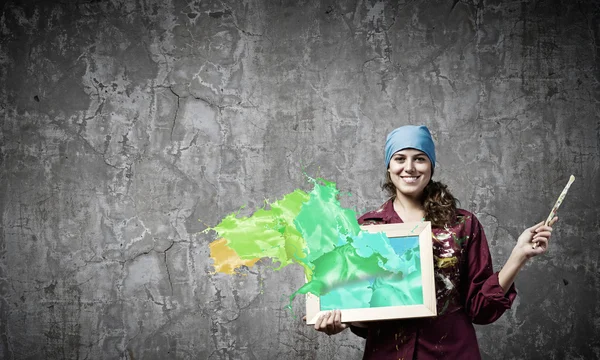 Pintor sosteniendo marco con salpicaduras de colores — Foto de Stock