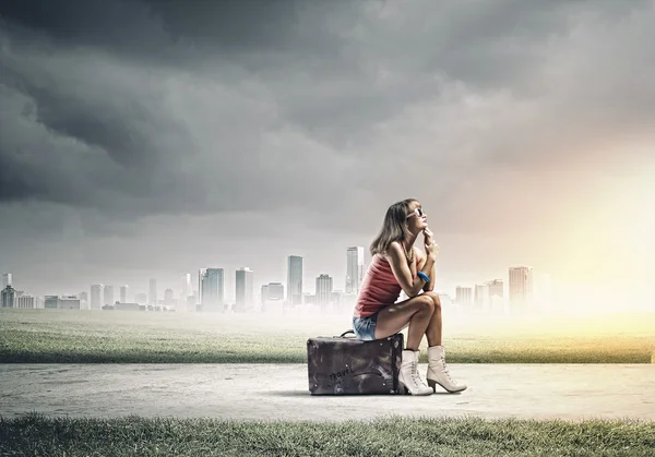 Девушка-путешественница сидит на чемодане — стоковое фото