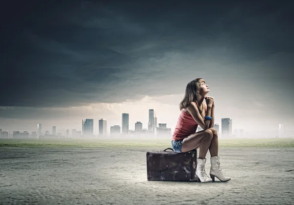 Девушка-путешественница сидит на чемодане — стоковое фото