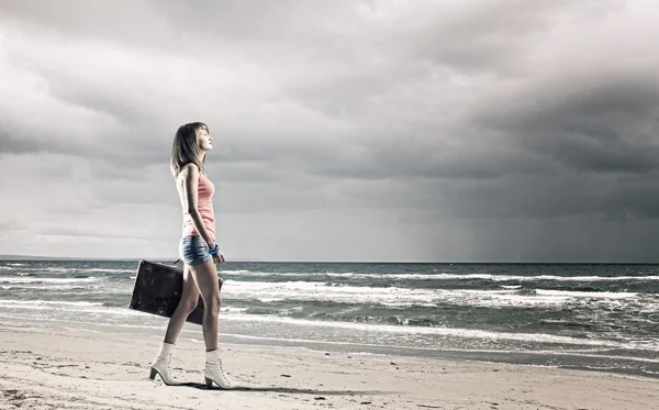 Mujer caminando con maleta a la orilla del mar — Foto de Stock
