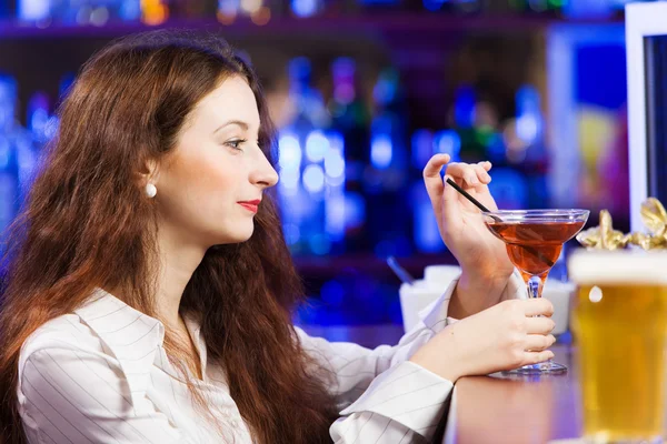 Девушка в баре пьет коктейль — стоковое фото