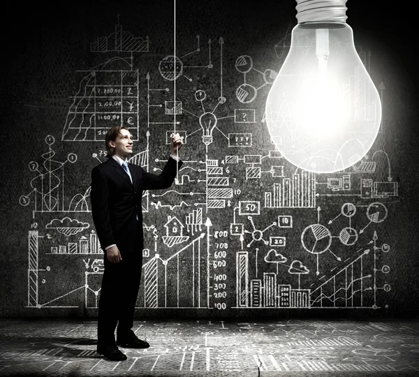 Businessman switching on light bulb — Stock Photo, Image