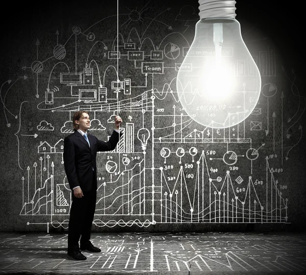 Businessman switching on light bulb — Stock Photo, Image