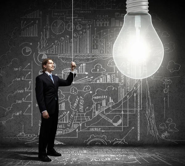 Businessman switching on light bulb — Stock Photo, Image