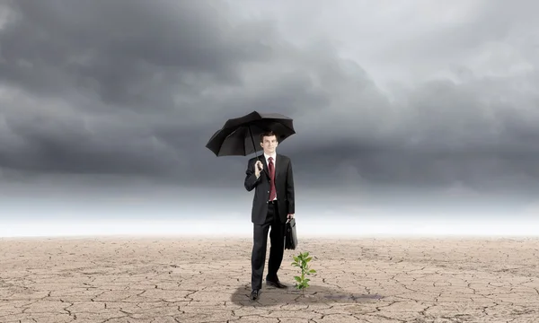 Geschäftsmann mit schützendem Regenschirm — Stockfoto