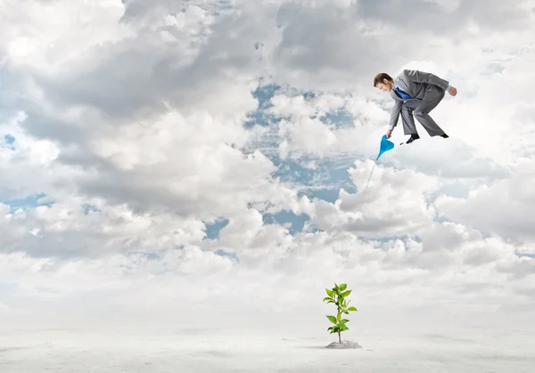 Geschäftsmann steht auf Wolke sieben und gießt Sprosse — Stockfoto