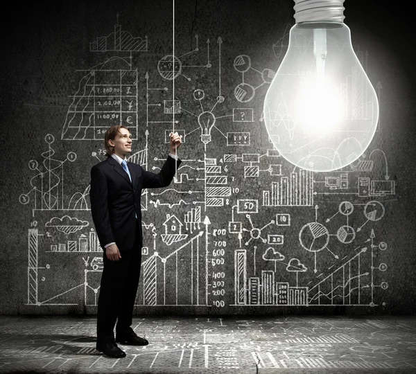 Businessman switching on light bulb — Stock Photo, Image