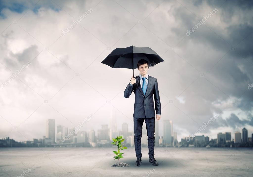 Businessman with umbrella protecting sprout