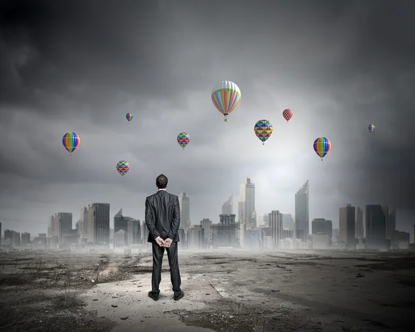 Uomo d'affari che guarda palloncini — Foto Stock