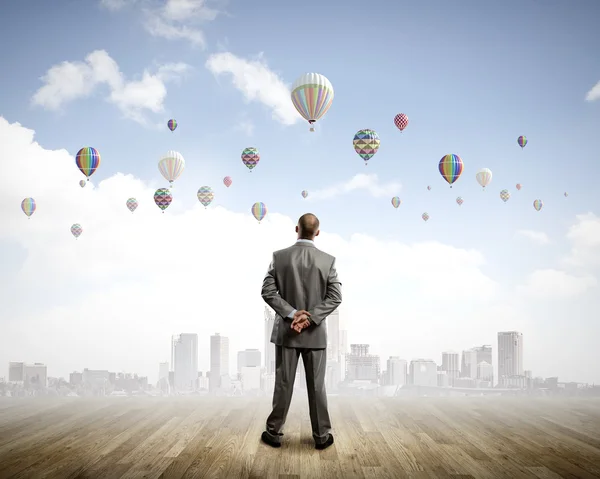 Uomo d'affari che guarda palloncini — Foto Stock