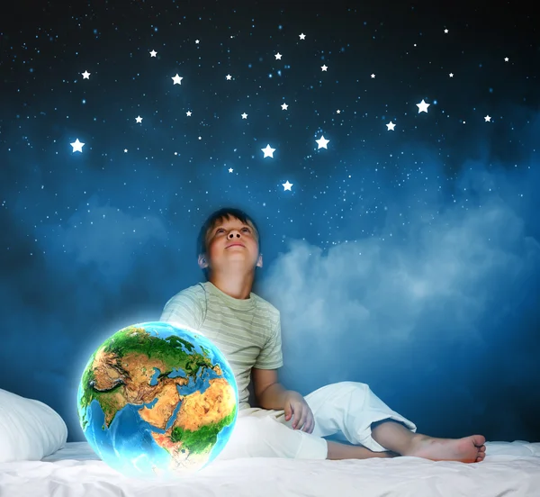 Boy sitting in bed and holding Earth planet — Stock Photo, Image