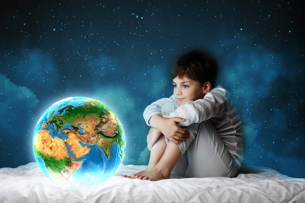 Boy sitting in bed and looking at Earth planet — Stock Photo, Image