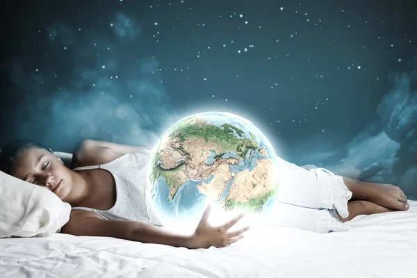 Девушка спит в постели и держит планету Земля — стоковое фото