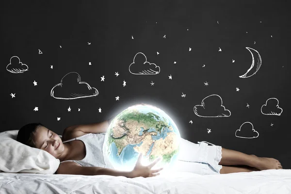 Girl lying in bed with Earth planet — Stock Photo, Image