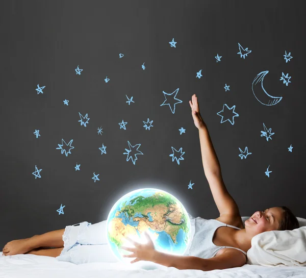 Menina deitada na cama e olhando para o planeta Terra — Fotografia de Stock