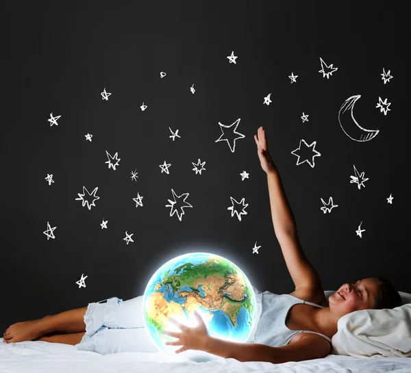 Chica acostada en la cama y mirando al planeta Tierra — Foto de Stock