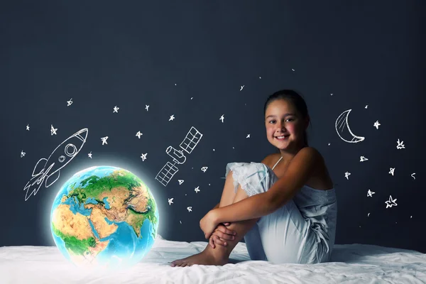 Mädchen sitzt im Bett und schaut auf den Planeten Erde — Stockfoto