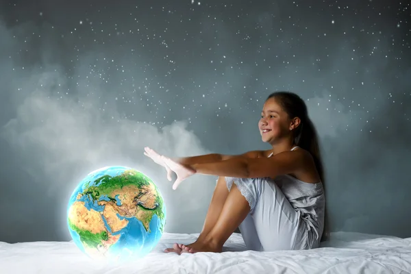 Girl sitting in bed and looking at Earth planet — Stock Photo, Image