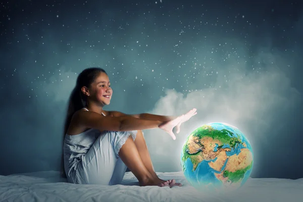 Girl sitting in bed and looking at Earth planet — Stock Photo, Image