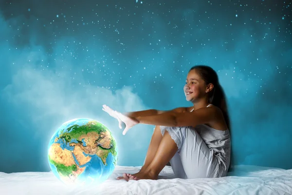 Meisje zitten in bed en kijken naar de planeet aarde — Stockfoto