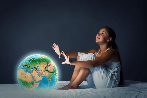 Girl sitting in bed and looking at Earth planet — Stock Photo, Image