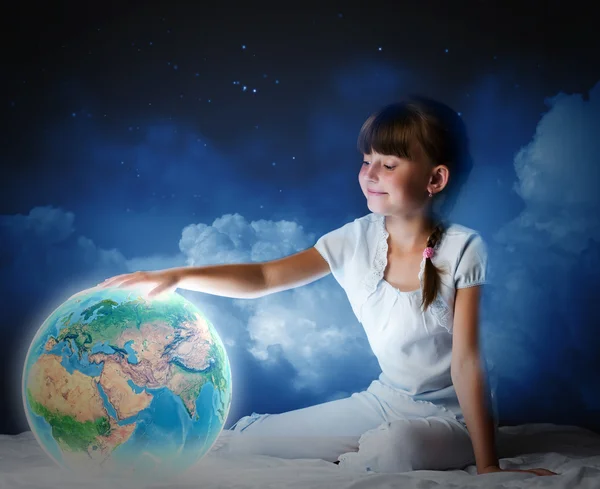 Menina sentada na cama e olhando para o planeta Terra — Fotografia de Stock