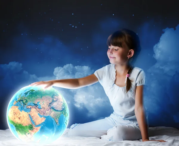 Chica sentada en la cama y mirando el planeta Tierra — Foto de Stock