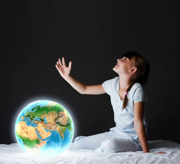 Menina sentada na cama e olhando para o planeta Terra — Fotografia de Stock