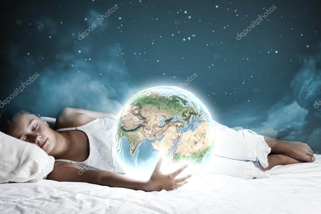 Girl sleeping in bed and holding Earth planet