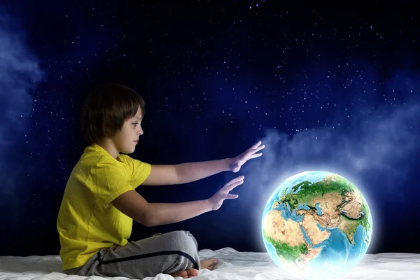 Boy sitting in bed holding Earth planet — Stock Photo, Image