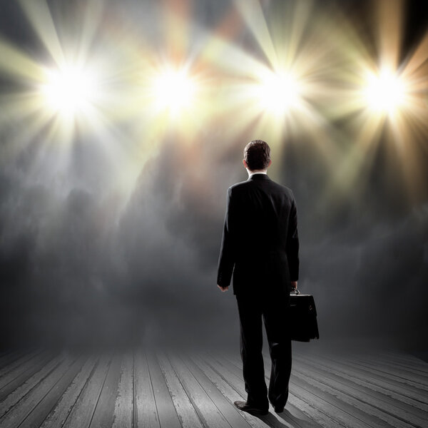 Businessman standing in lights of stage