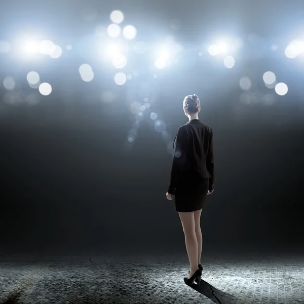 Businesswoman standing in lights of stage — Stock Photo, Image