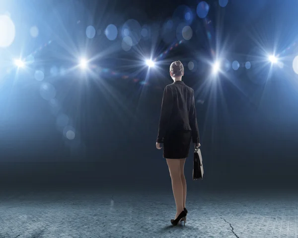 Businesswoman standing in lights of stage — Stock Photo, Image