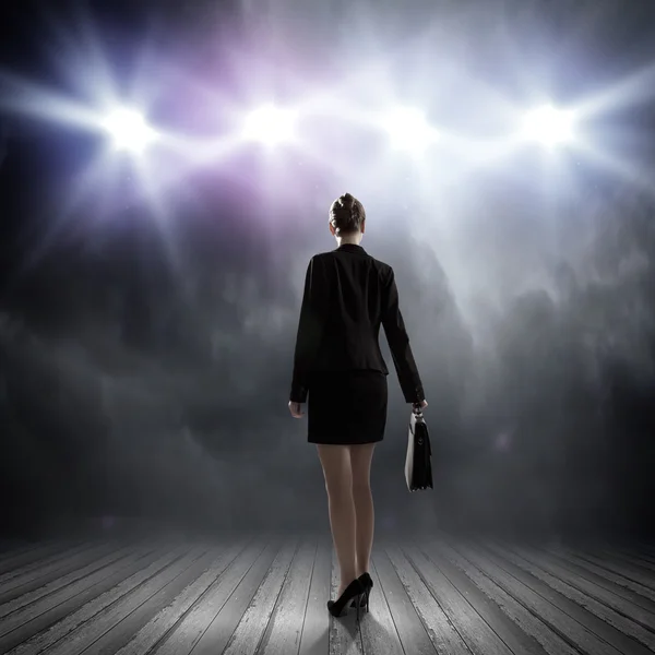 Businesswoman standing in lights of stage — Stock Photo, Image