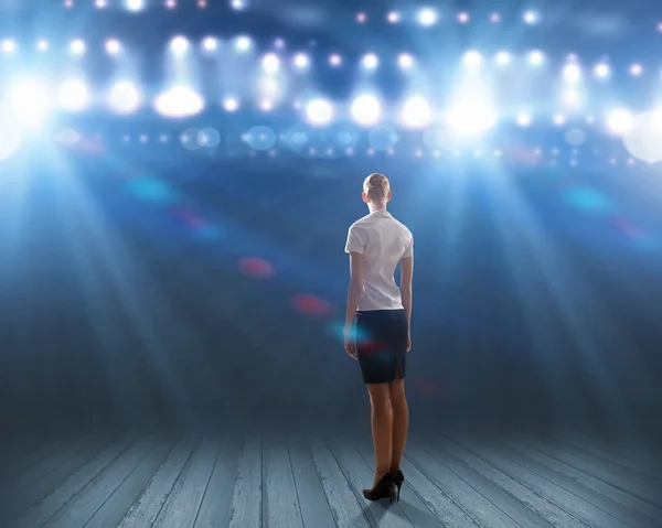 Businesswoman standing in lights of stage — Stock Photo, Image