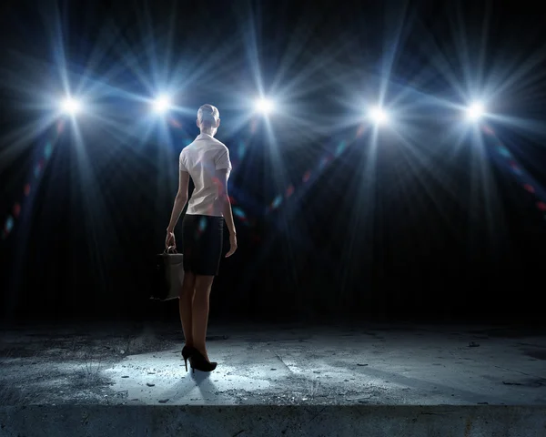 Businesswoman standing in lights of stage — Stock Photo, Image