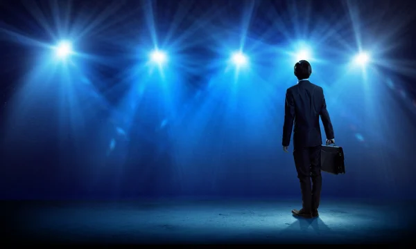 Businessman standing in lights of stage — Stock Photo, Image