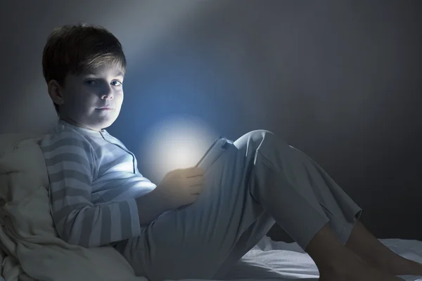 Boy using tablet pc in bed — Stock Photo, Image