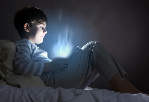 Boy using tablet pc in bed — Stock Photo, Image